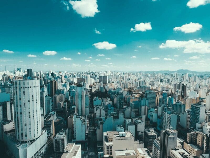 A vast cityscape under a bright blue sky with scattered clouds. A vast cityscape under a bright blue sky with scattered clouds.